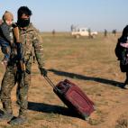 Un miembro de las milicias kurdas atiende a una mujer y a su beb&eacute;, reci&eacute;n escapados de Baghouz.
