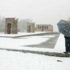 Un hombre con paraguas aparece cerca del templo de Debod, un templo egipcio antiguo reconstruido en Madrid, cubierto por la fuerte nevada.
